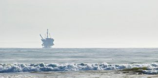 Surfers wait for waves with an offshore drilling platform in the distance in Santa Barbara, CA. Photo: Berardo62, Flickr CC.